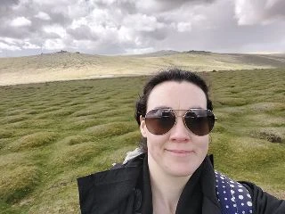 Person standing in a scenic countryside setting.