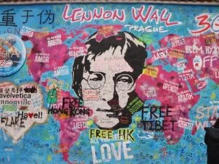 Colourful mural at Lennon Wall in Prague featuring a portrait of John Lennon surrounded by messages promoting peace and freedom.